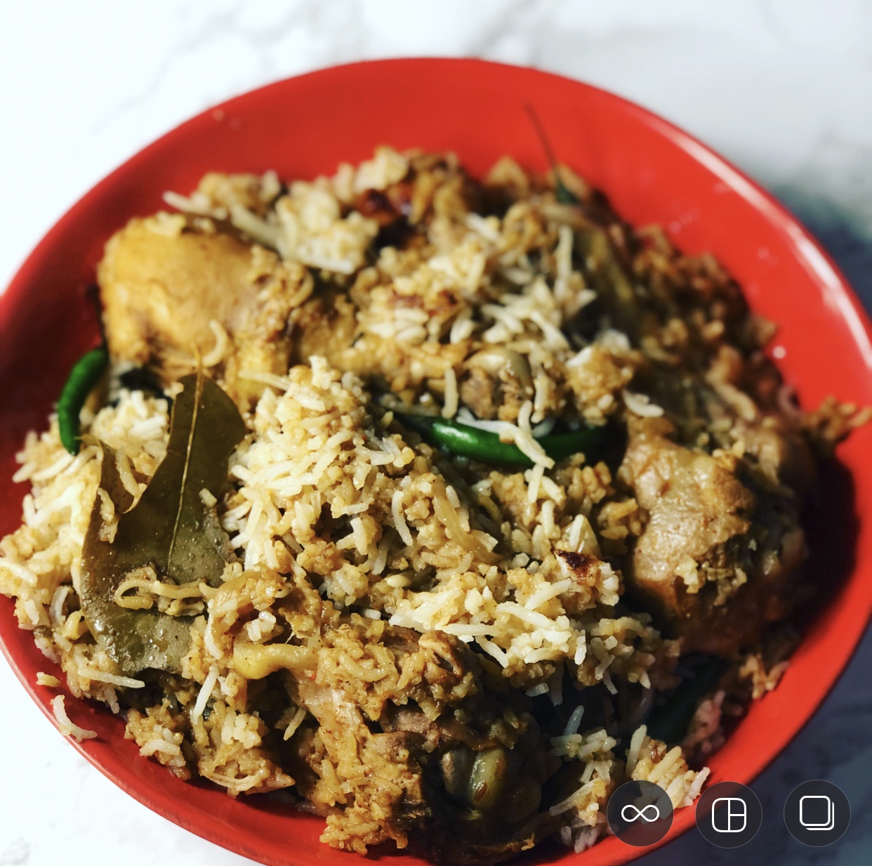A bowl of rice, chicken, chili peppers and bay leaves.