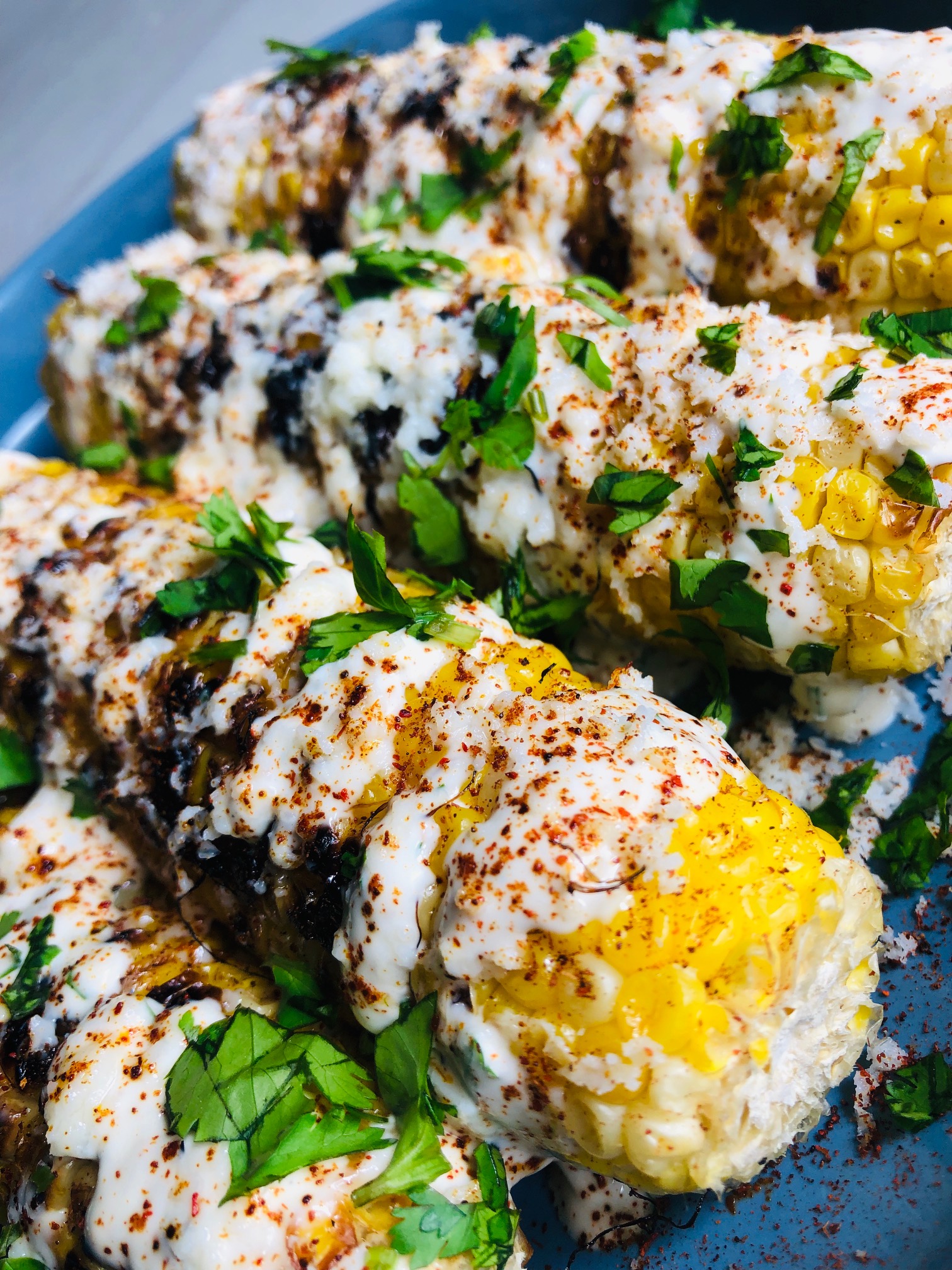 Grilled Corn on the Cob smothered in a crema sauce, sprinkled with chili powder and topped with cojita cheese and cilantro.
