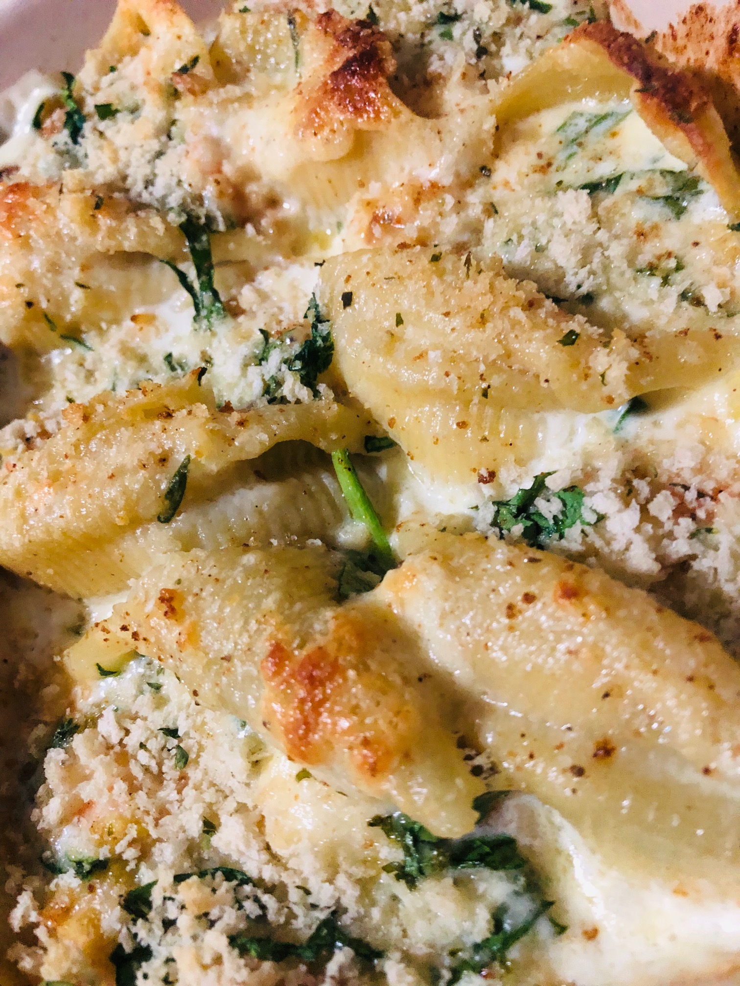 Jumbo pasta shells stuffed with seafood, spinach, and cream sauce topped with panko crumbs and parmesan cheese