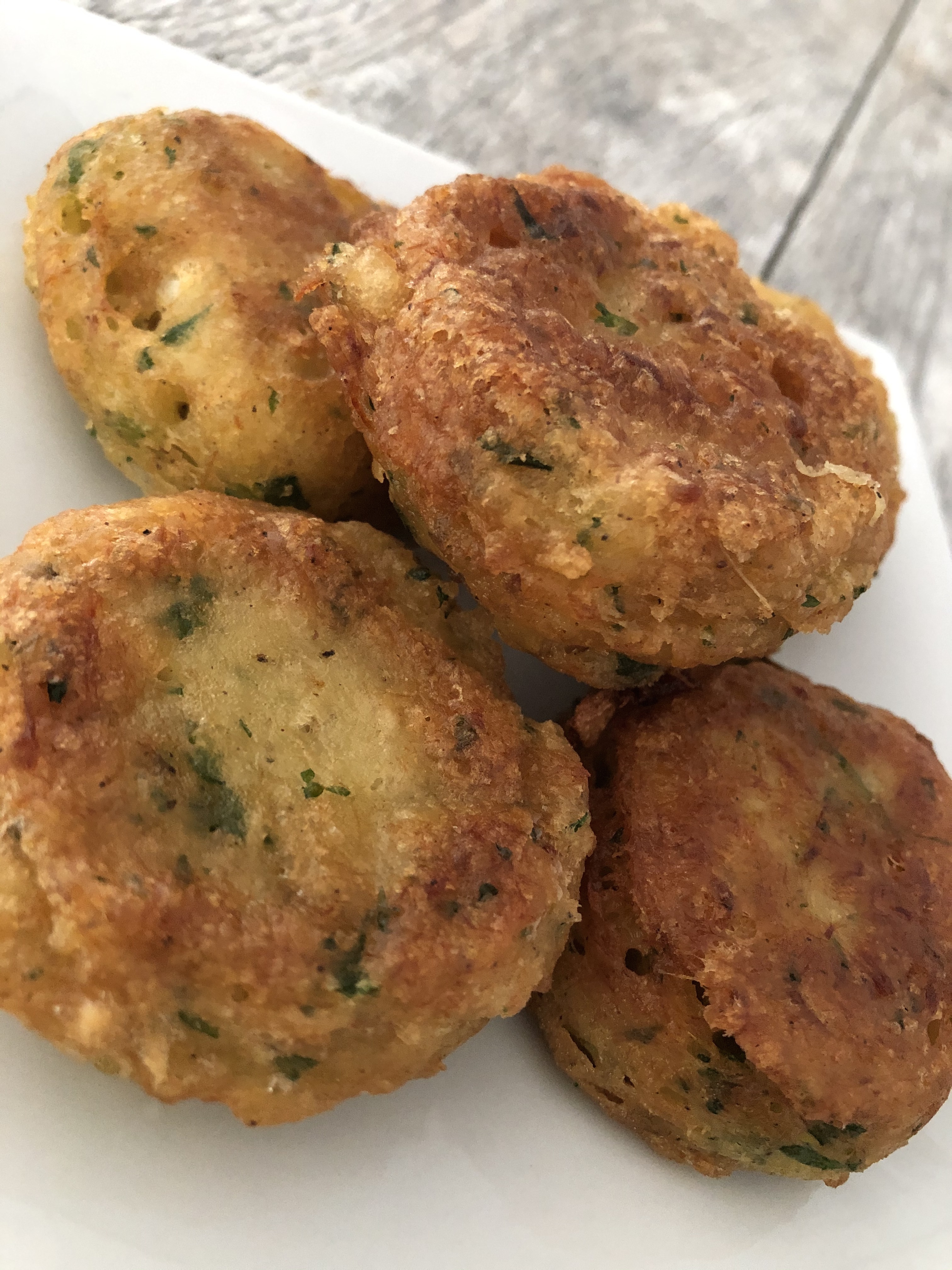 Bajan Fish Cakes fried to perfection and stacked on a square porcelain appetizer plate.