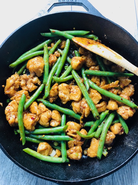 Green Bean and Chicken Breast Stir Fry in a Cast Iron Skillet with a wooden spoon.