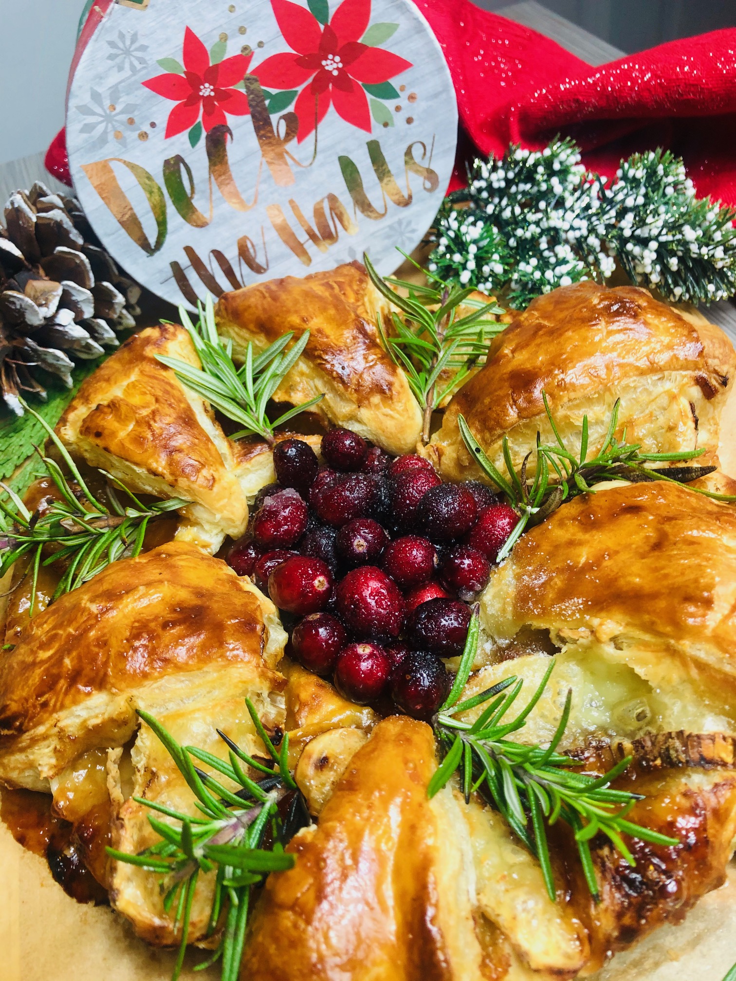 Golden brown puff pastry wreath filled with guava jam and baked brie with a center filled with candied cranberries